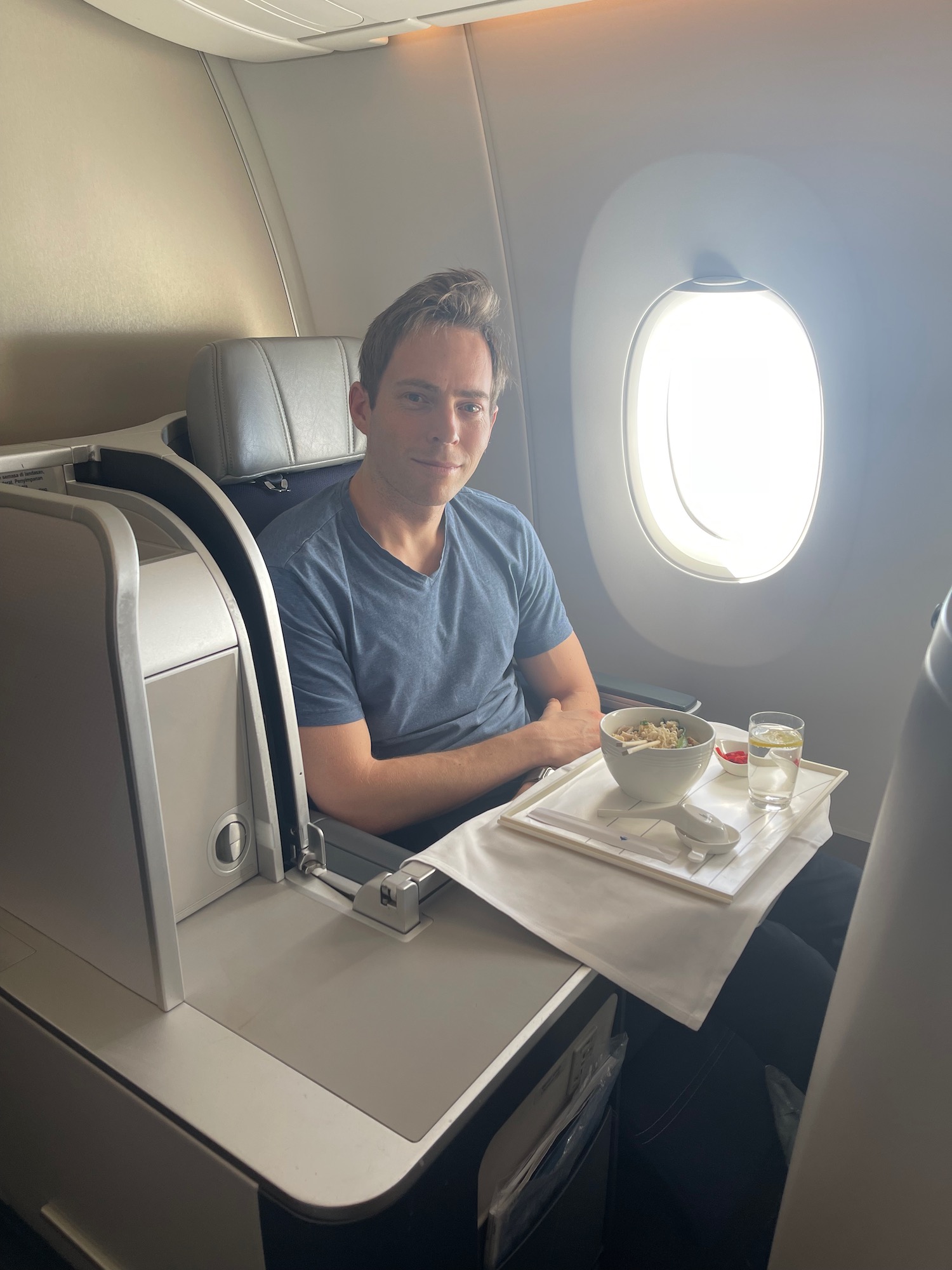 a man sitting in an airplane with a bowl of food