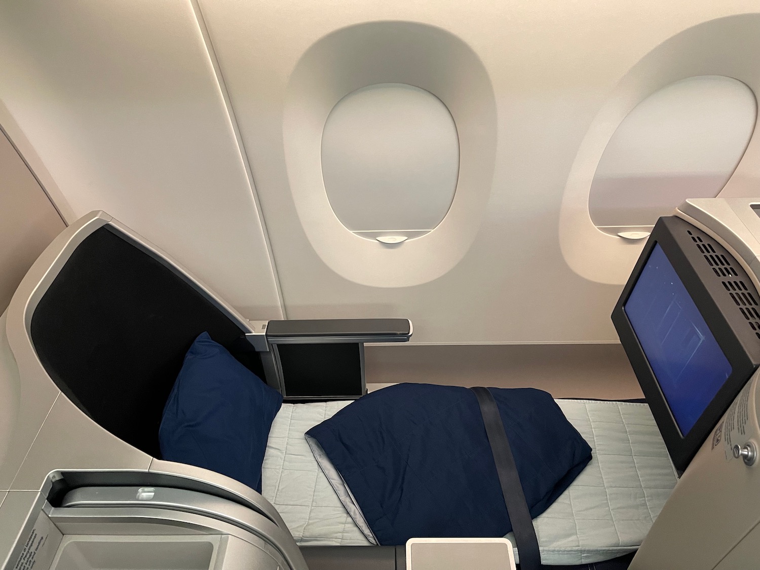 a bed with a computer monitor and a window in an airplane