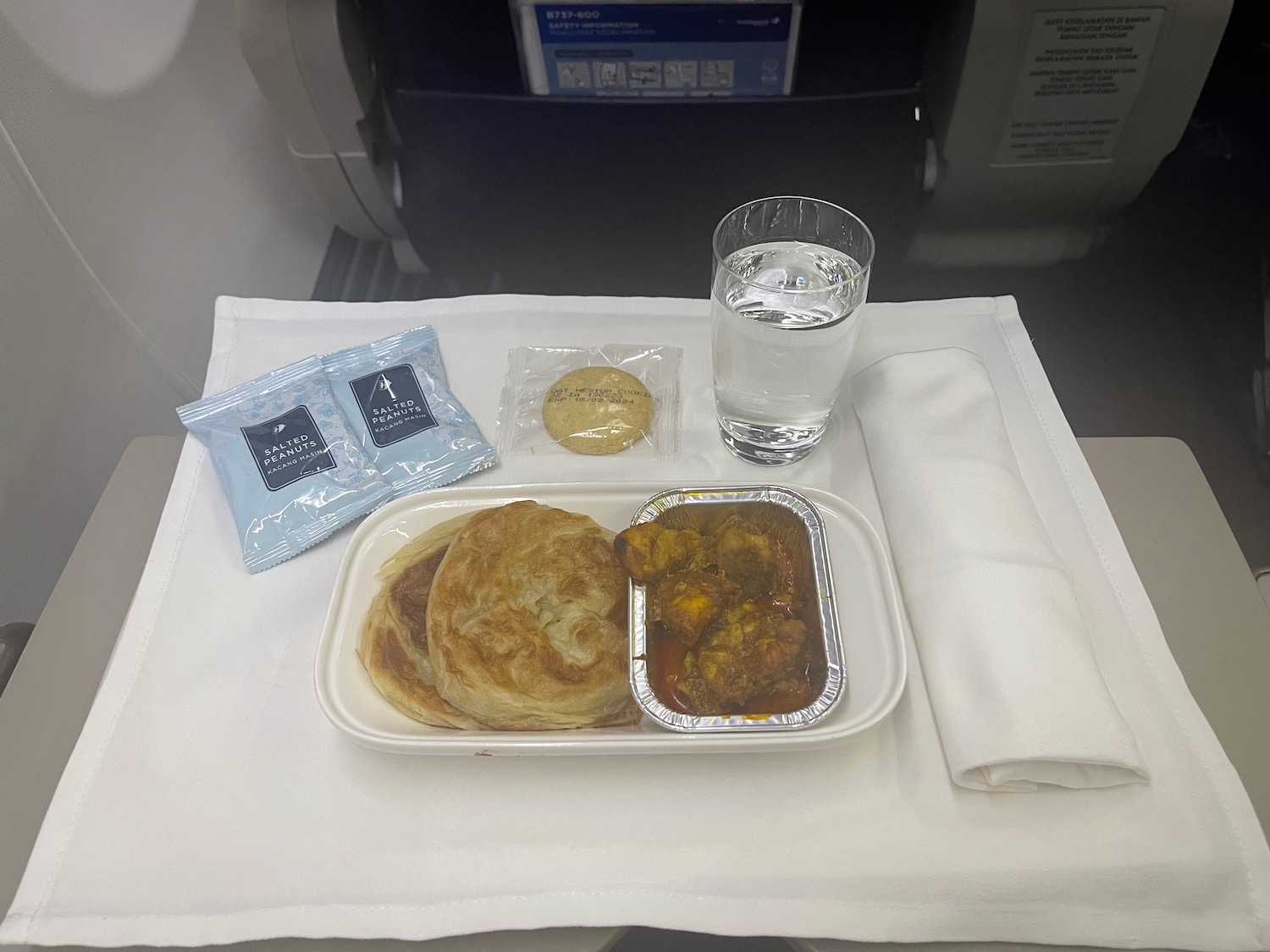 food on a tray with a glass of water and a napkin