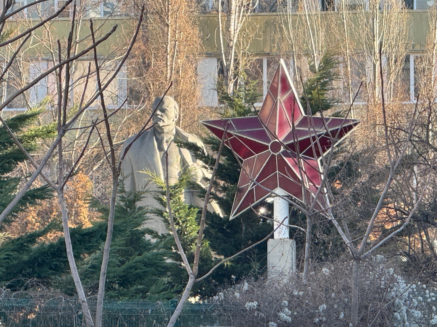 a statue of a man with a red star in front of a building