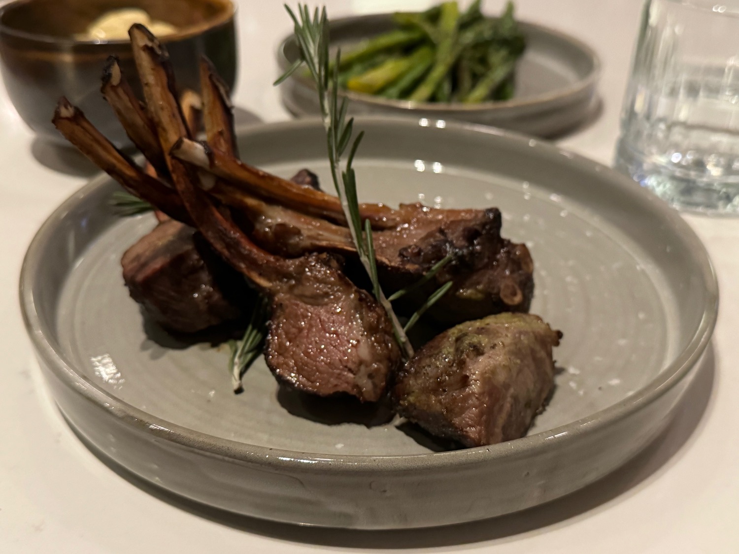a plate of meat with a rosemary sprig on it