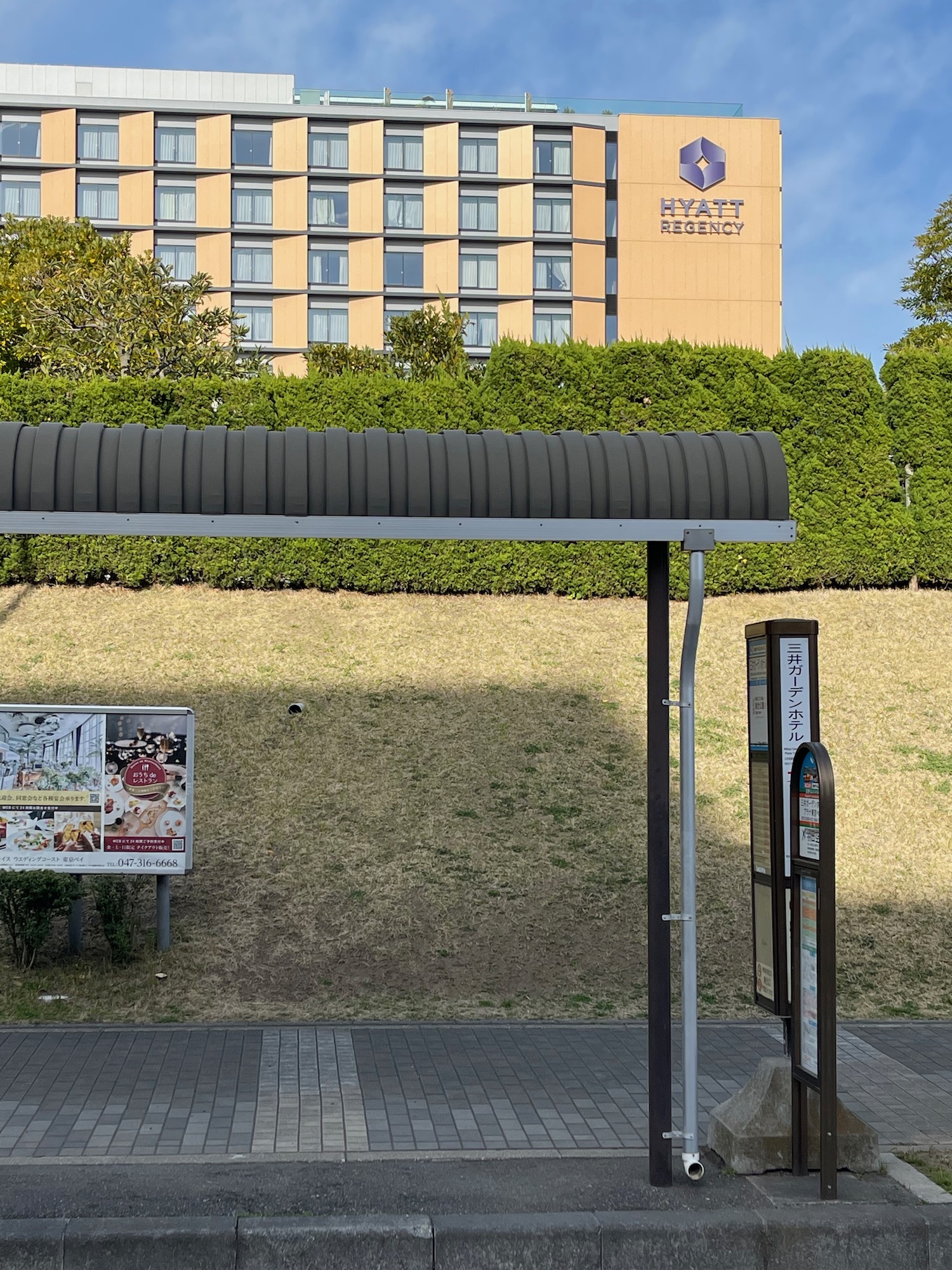 a bus stop with a sign and a building in the background