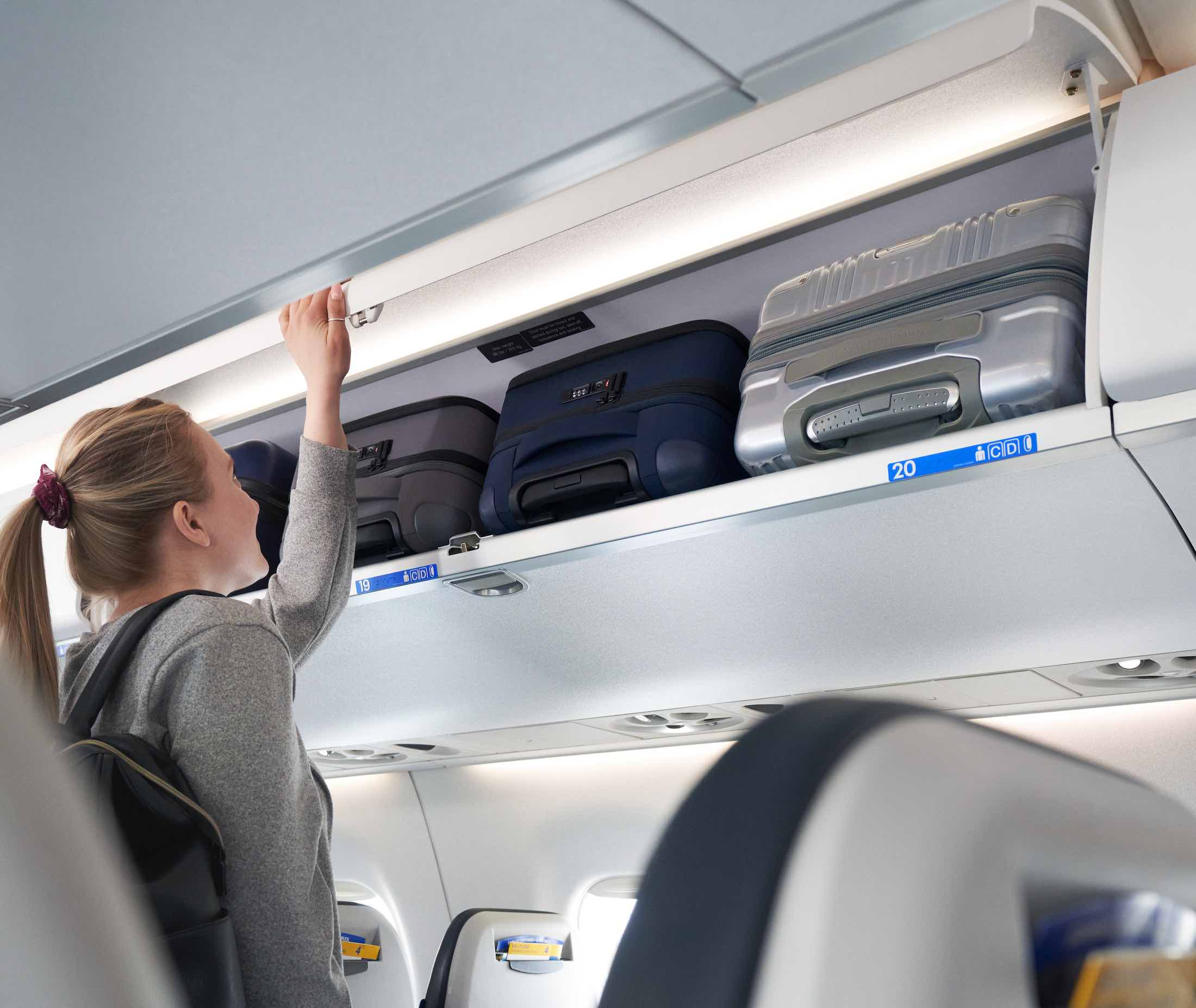 a woman putting luggage on a shelf