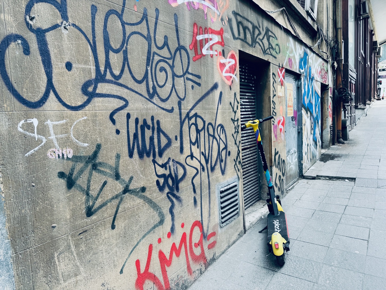 a scooter parked on a sidewalk next to a building with graffiti