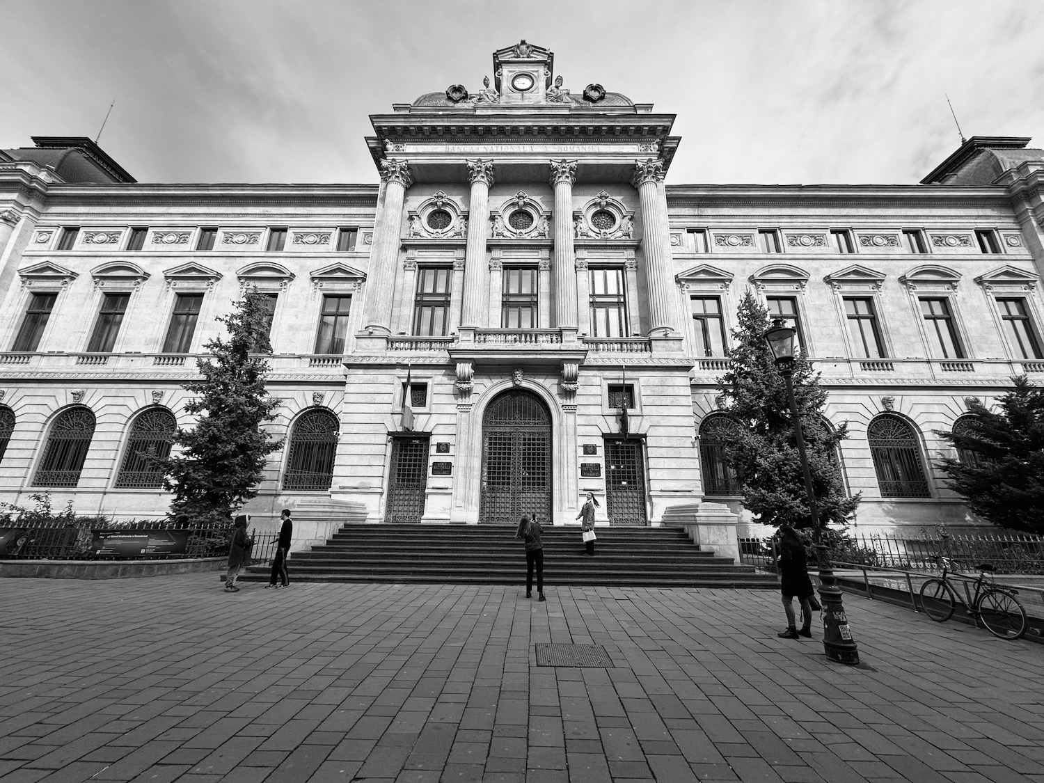 a large building with stairs and people walking in front