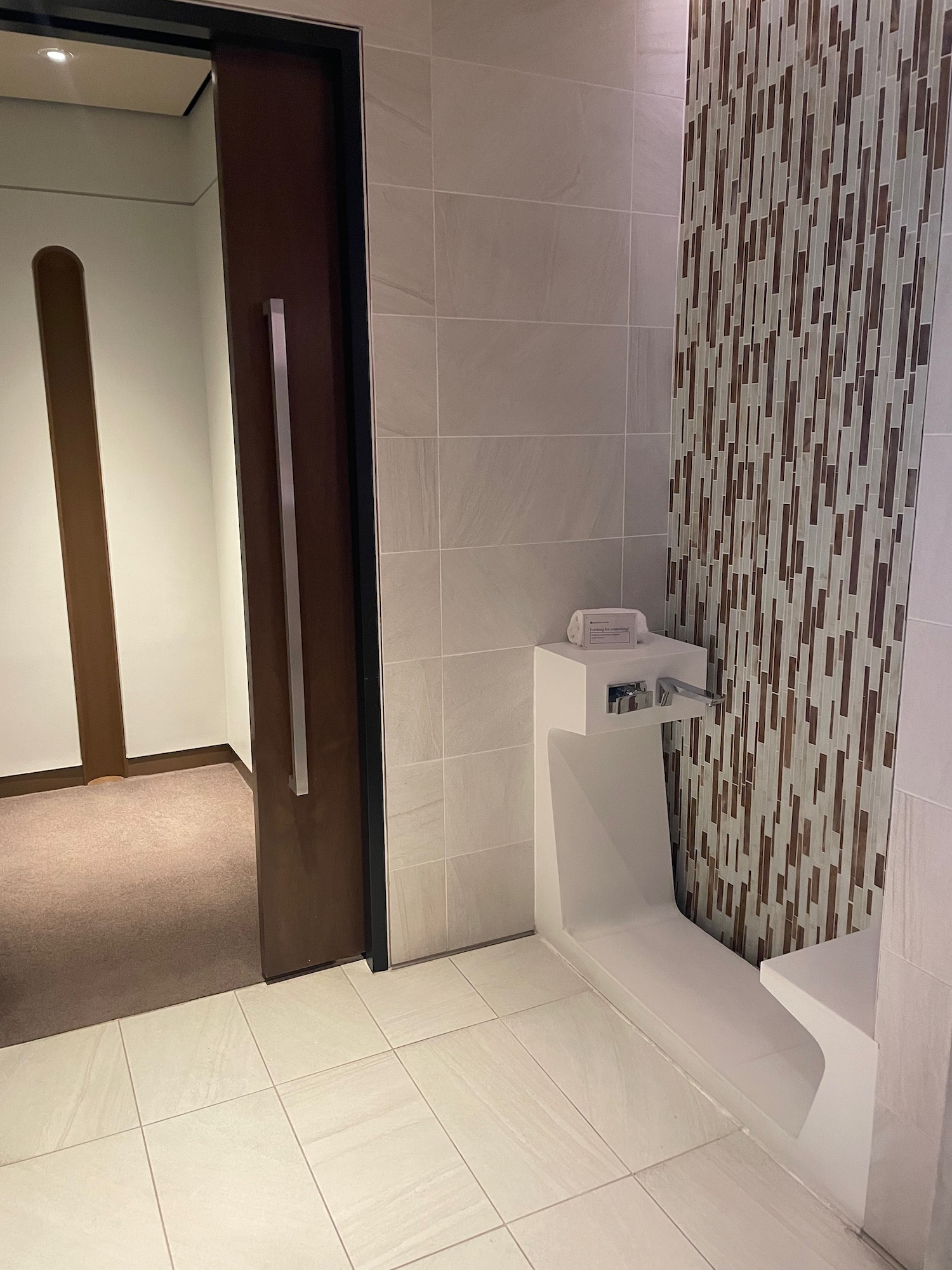 a bathroom with a white sink and brown tile wall
