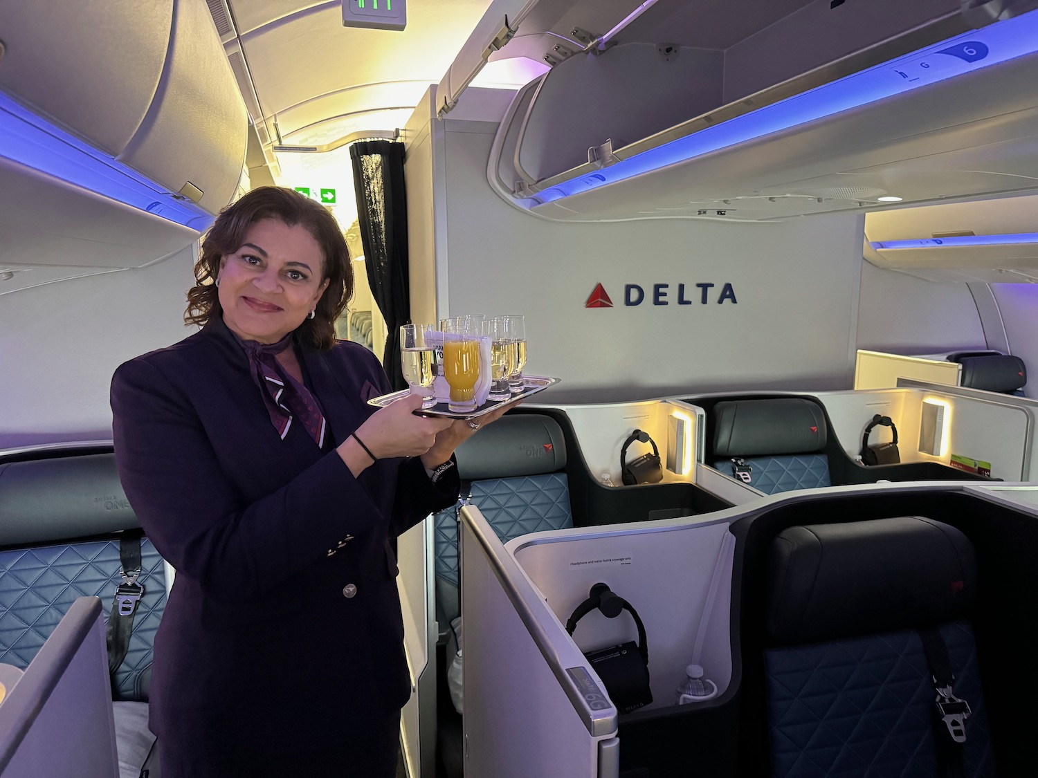 a woman holding a tray of drinks in a plane