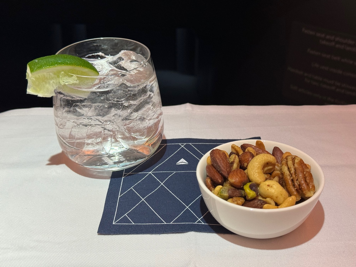 a bowl of nuts and a glass of water with a lime wedge