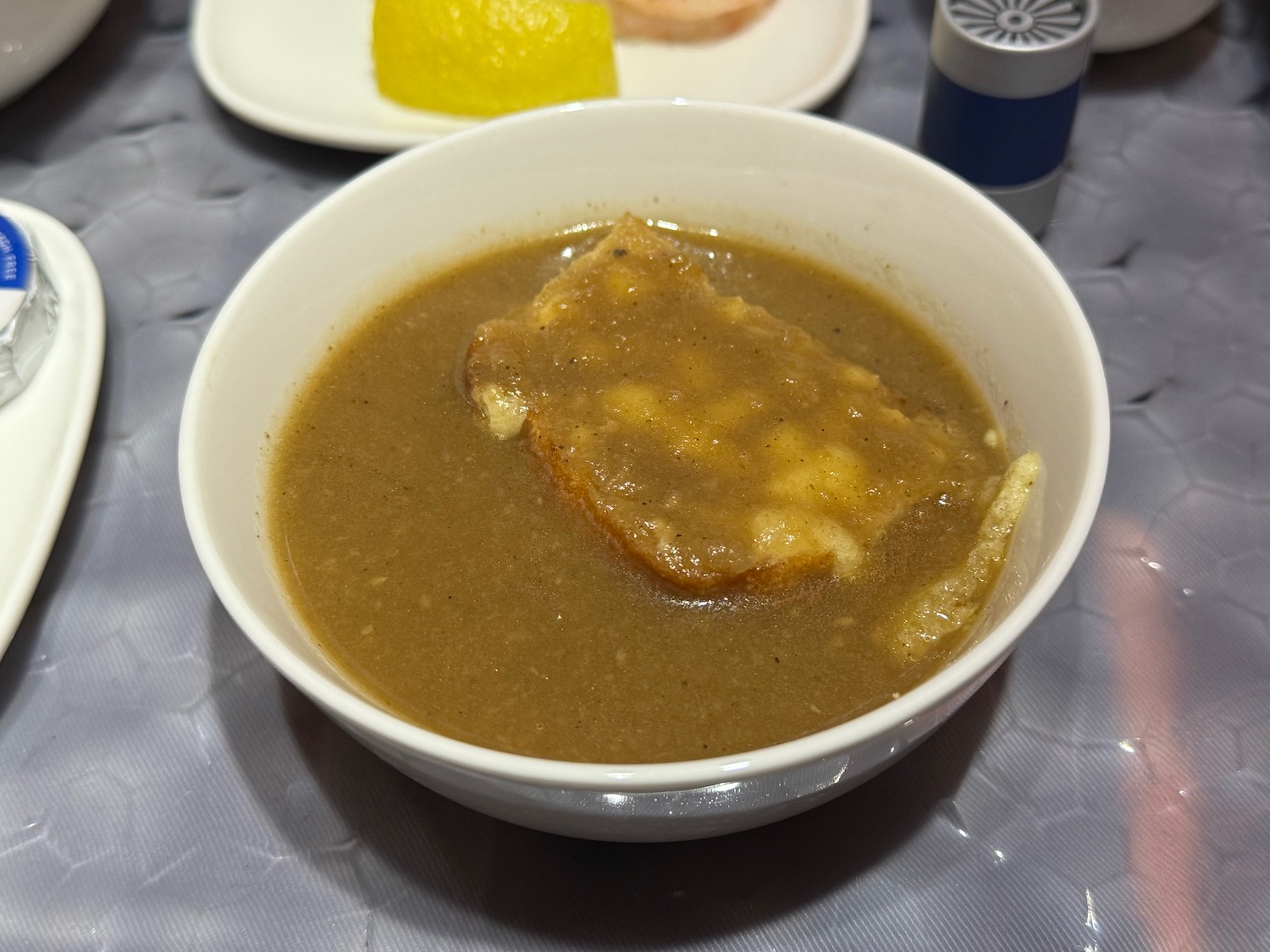 a bowl of brown soup with toast and a slice of bread