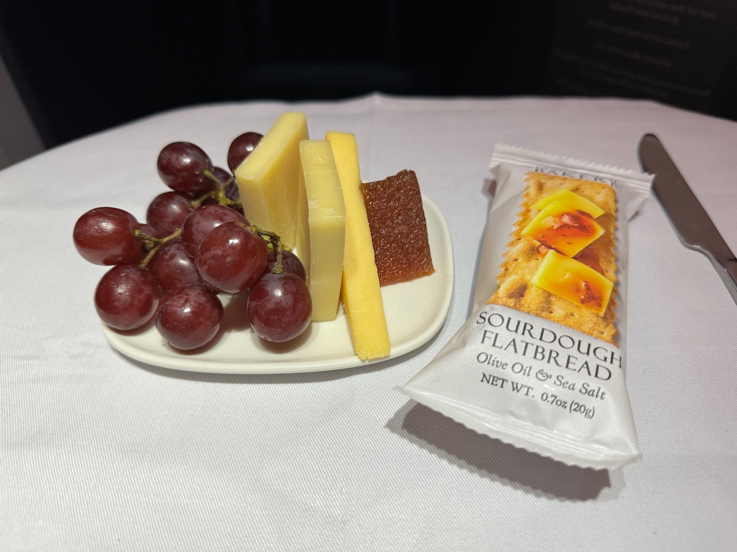 a plate of cheese grapes and a packet of bread