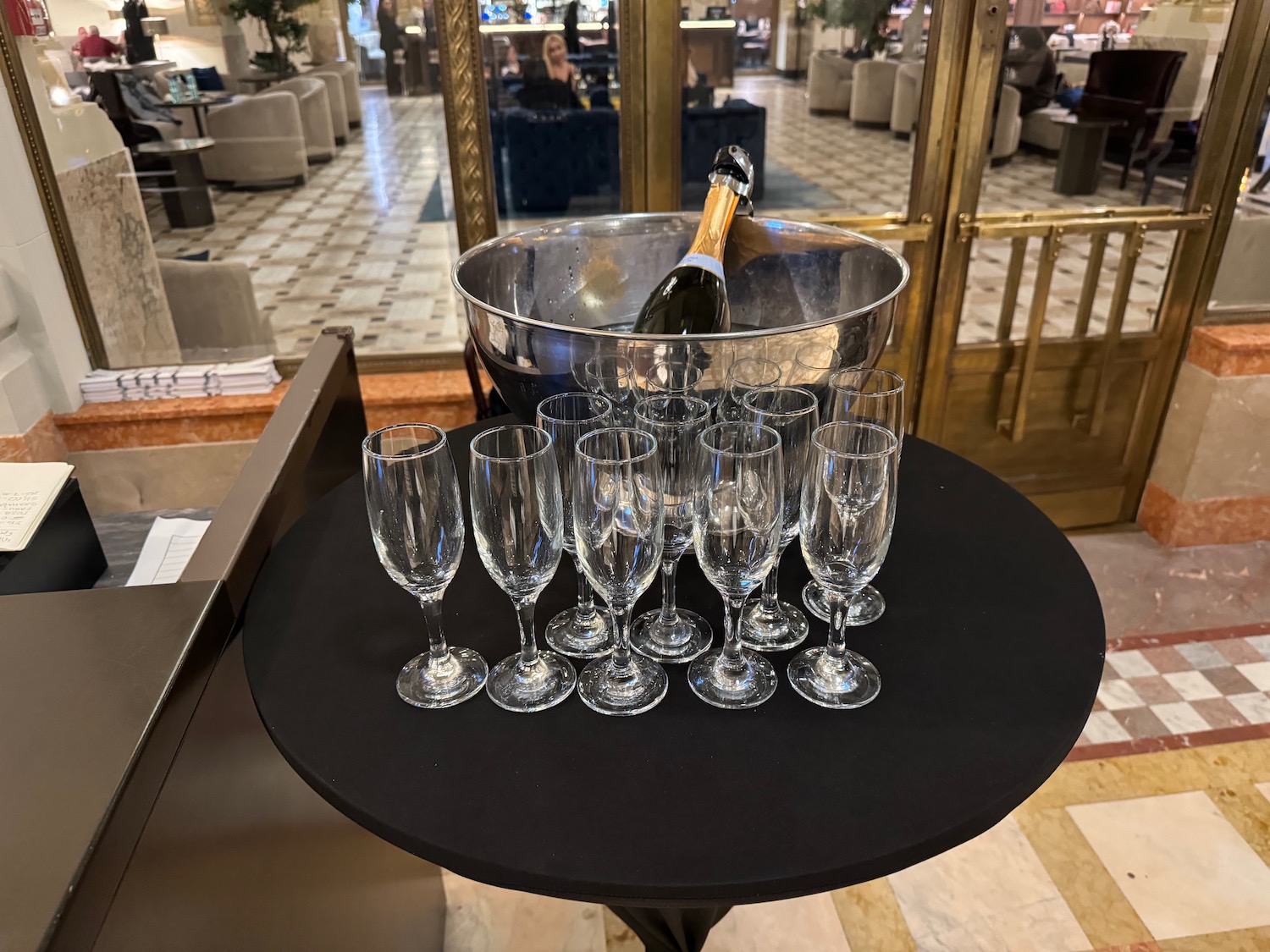 a champagne bottle in a bucket and several glasses on a table