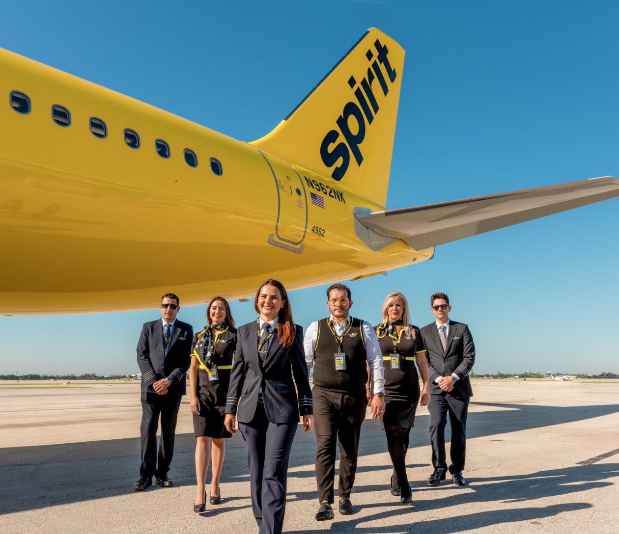 a group of people standing in front of a yellow airplane