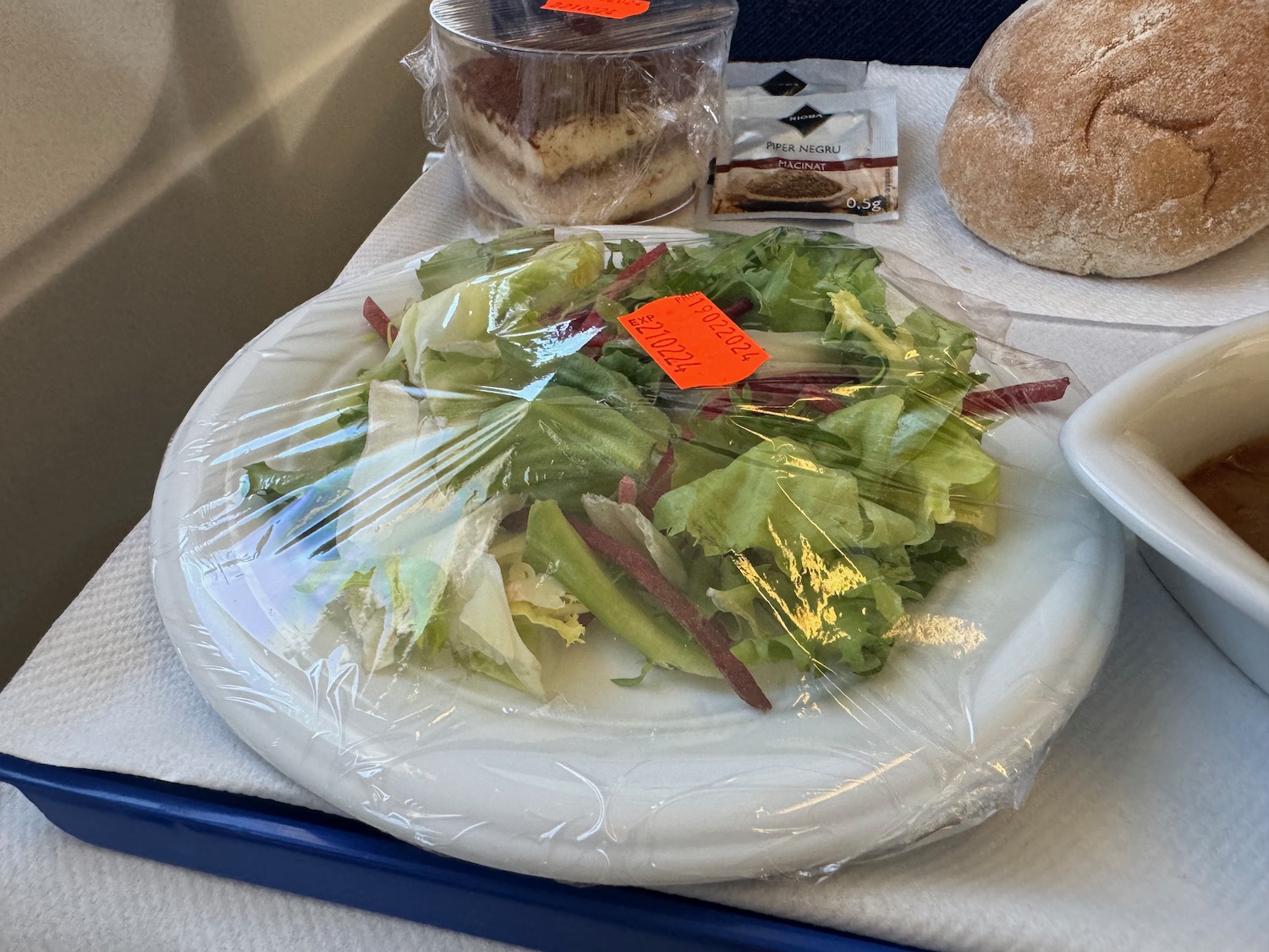 a plate of salad and bread on a tray