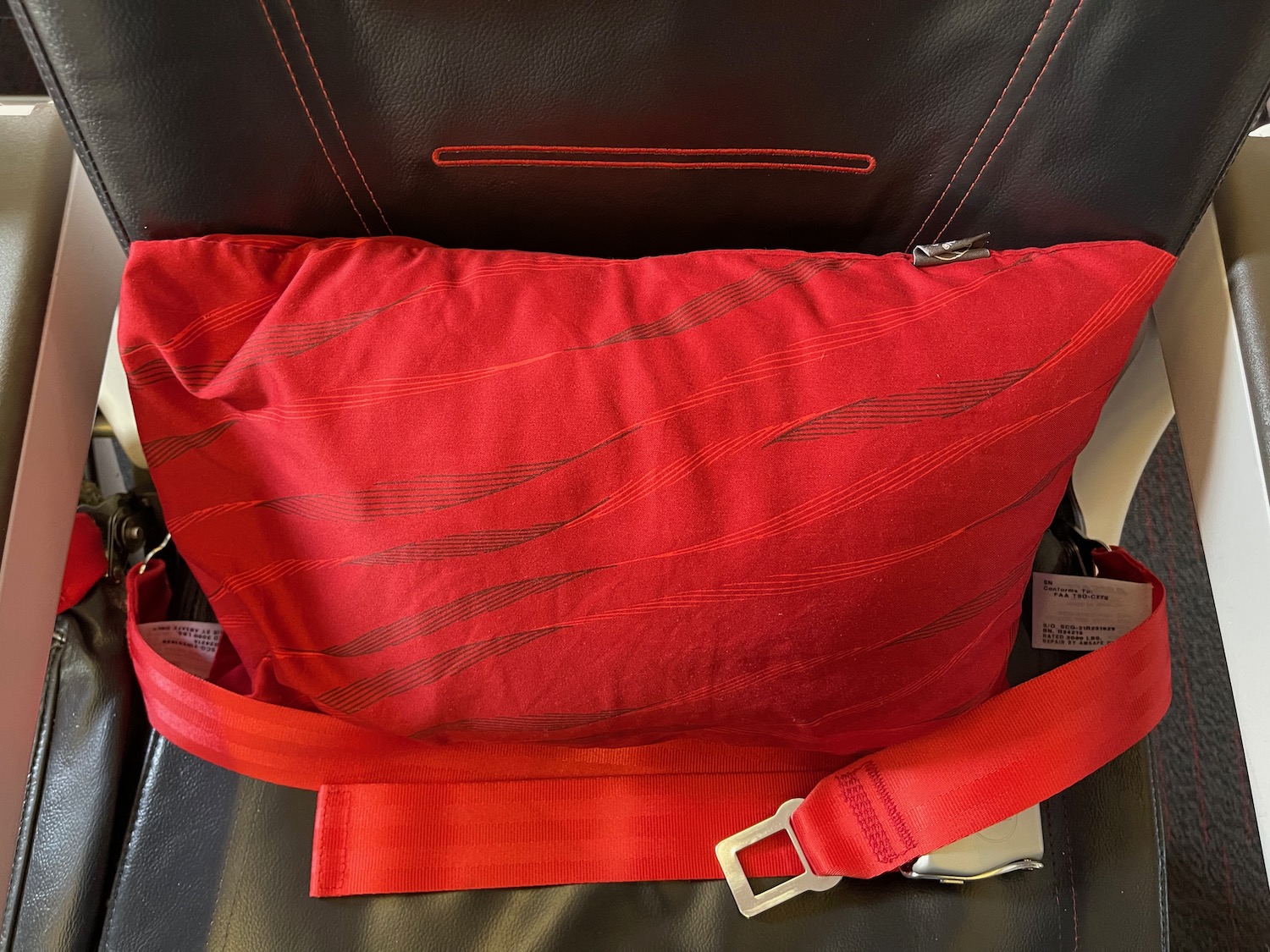 a red pillow with a red strap on a black leather chair
