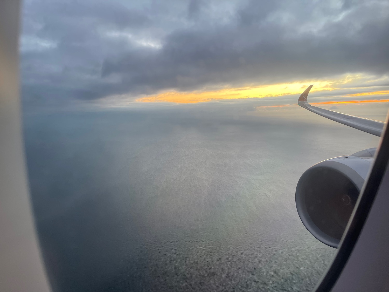 an airplane wing and engine above the ocean