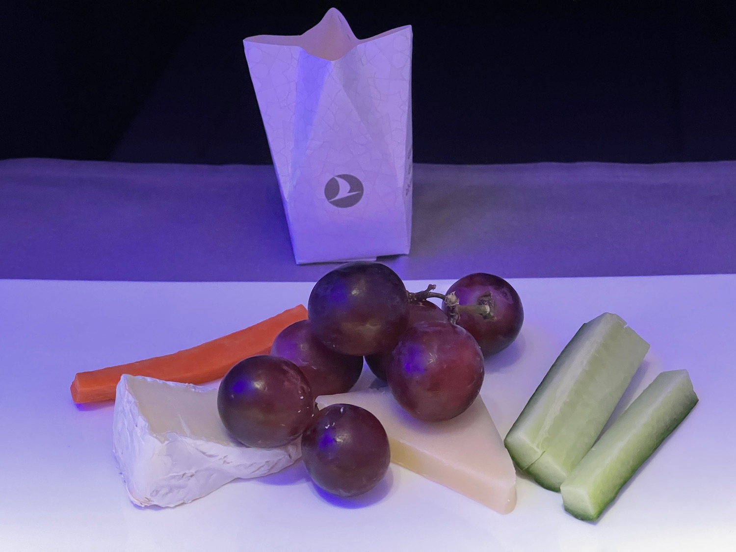 a plate of food with grapes and cucumber