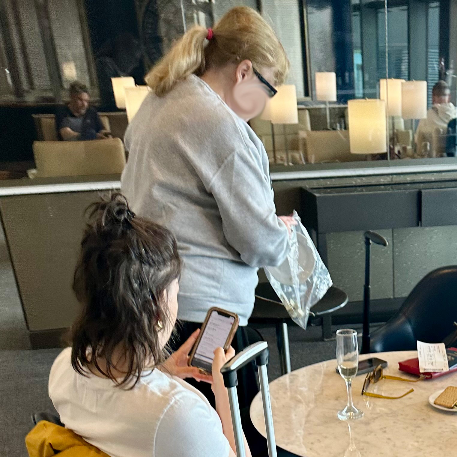 a woman standing behind a woman holding a phone