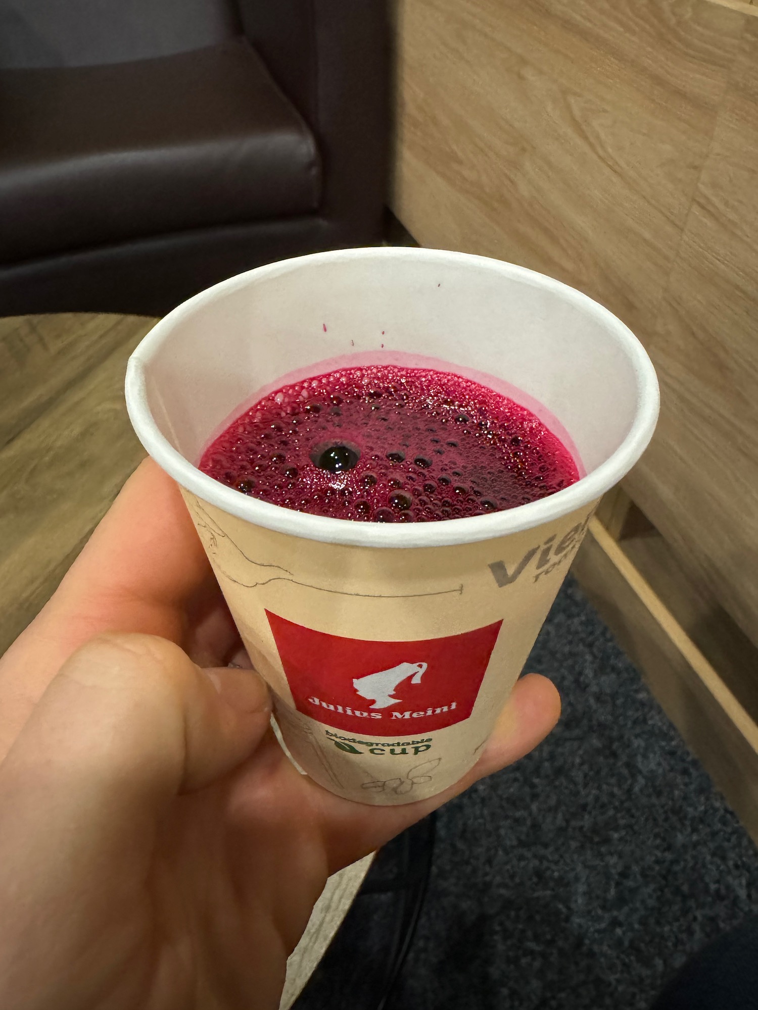 a hand holding a cup of red liquid
