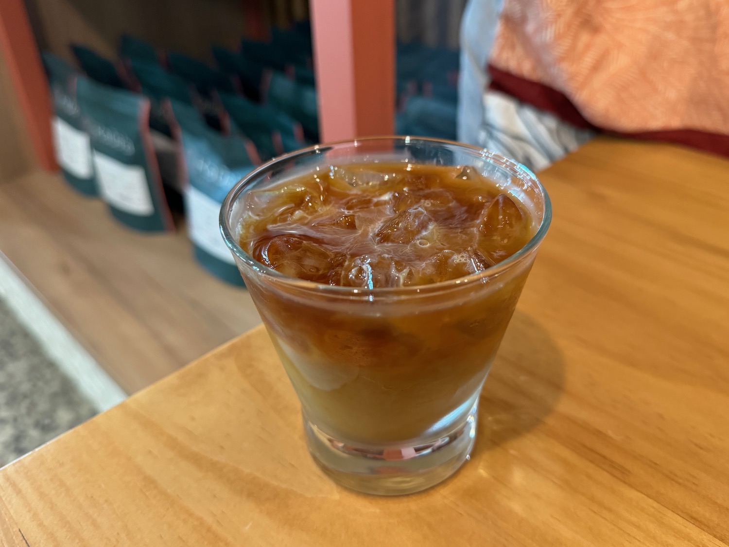 a glass of liquid with ice on a table