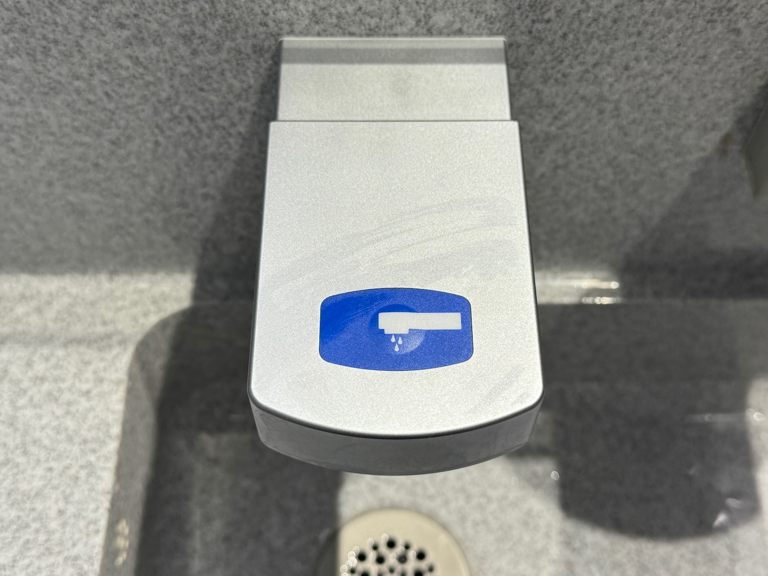 a grey soap dispenser with a blue and white logo