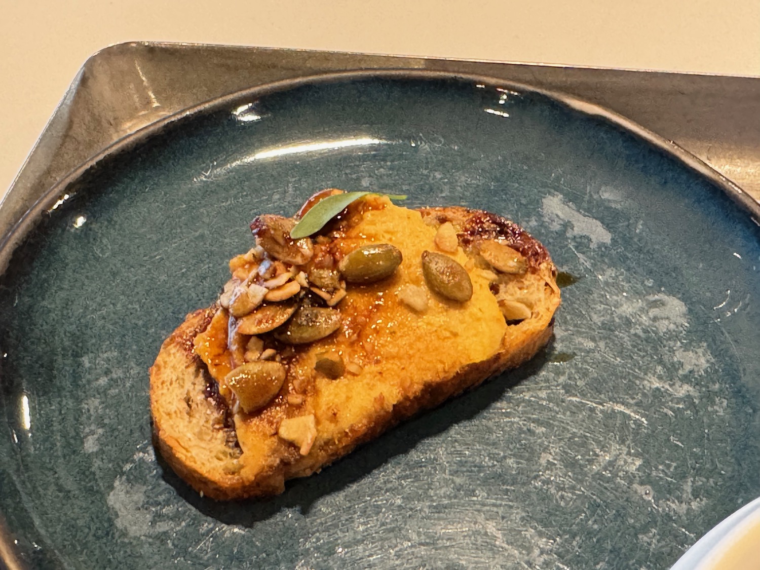 a piece of toast with peanut butter and seeds on a blue plate