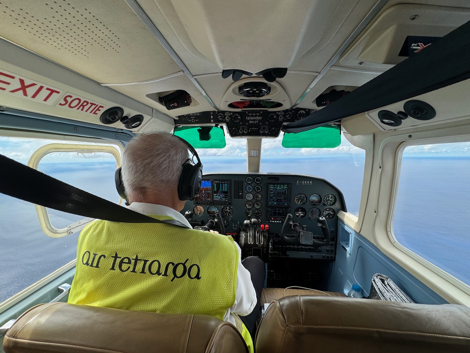 a man in a yellow vest in a cockpit of a plane