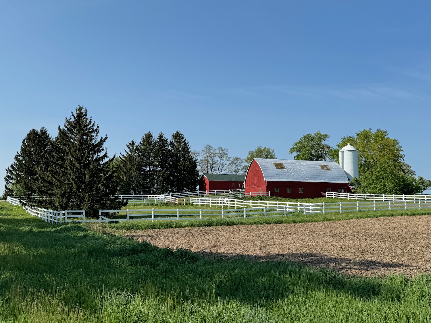 a farm with a white fence and a red barn