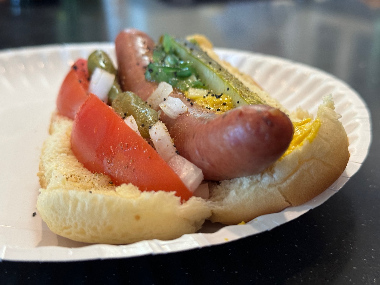 a hot dog with vegetables on a paper plate