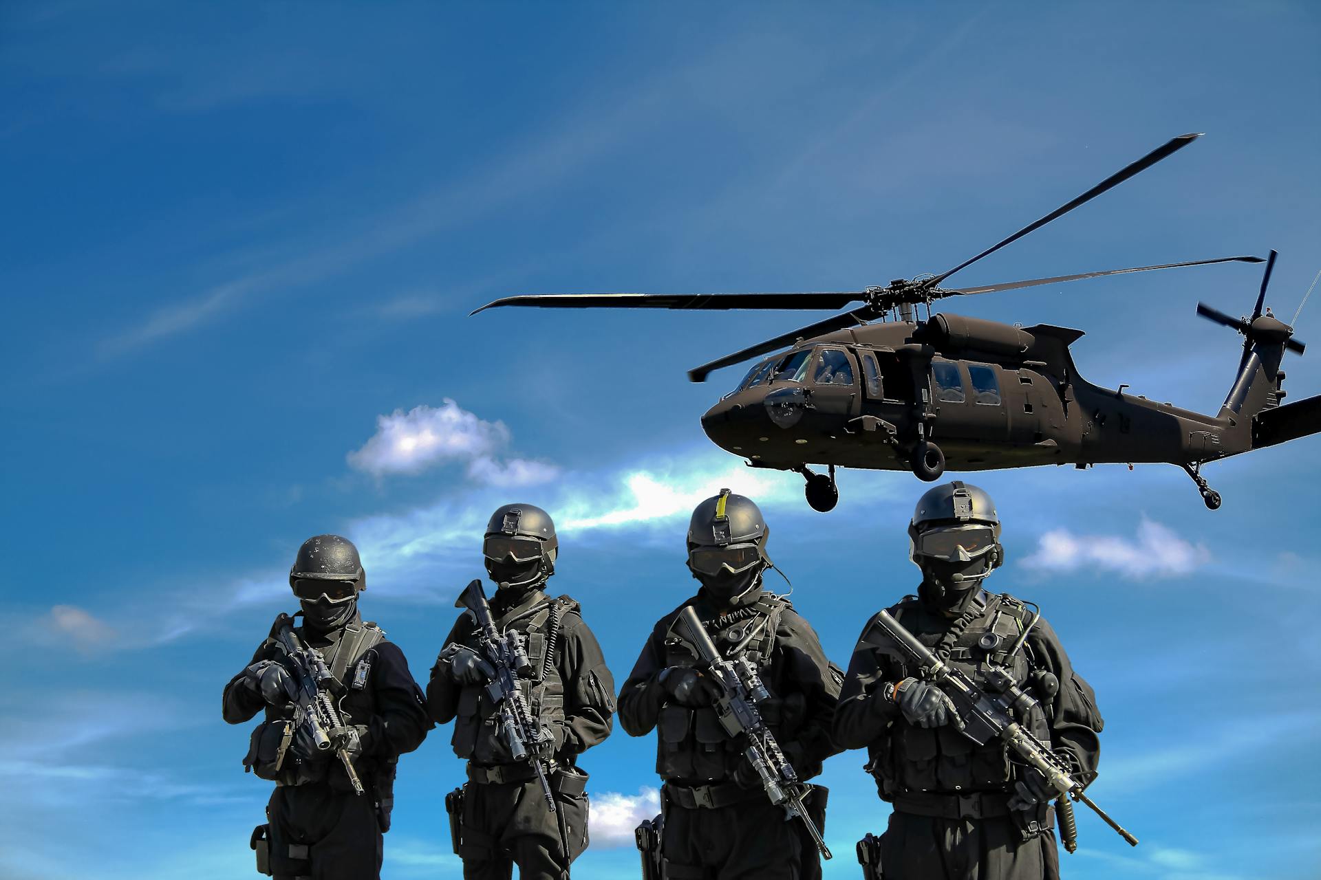 a group of people in uniform holding guns and a helicopter