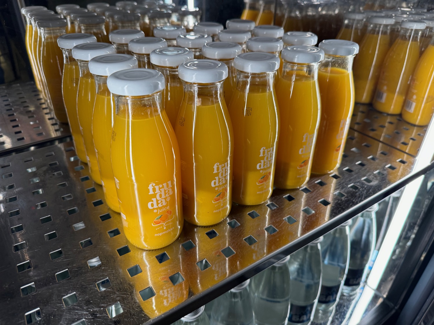 a group of bottles of orange juice on a shelf