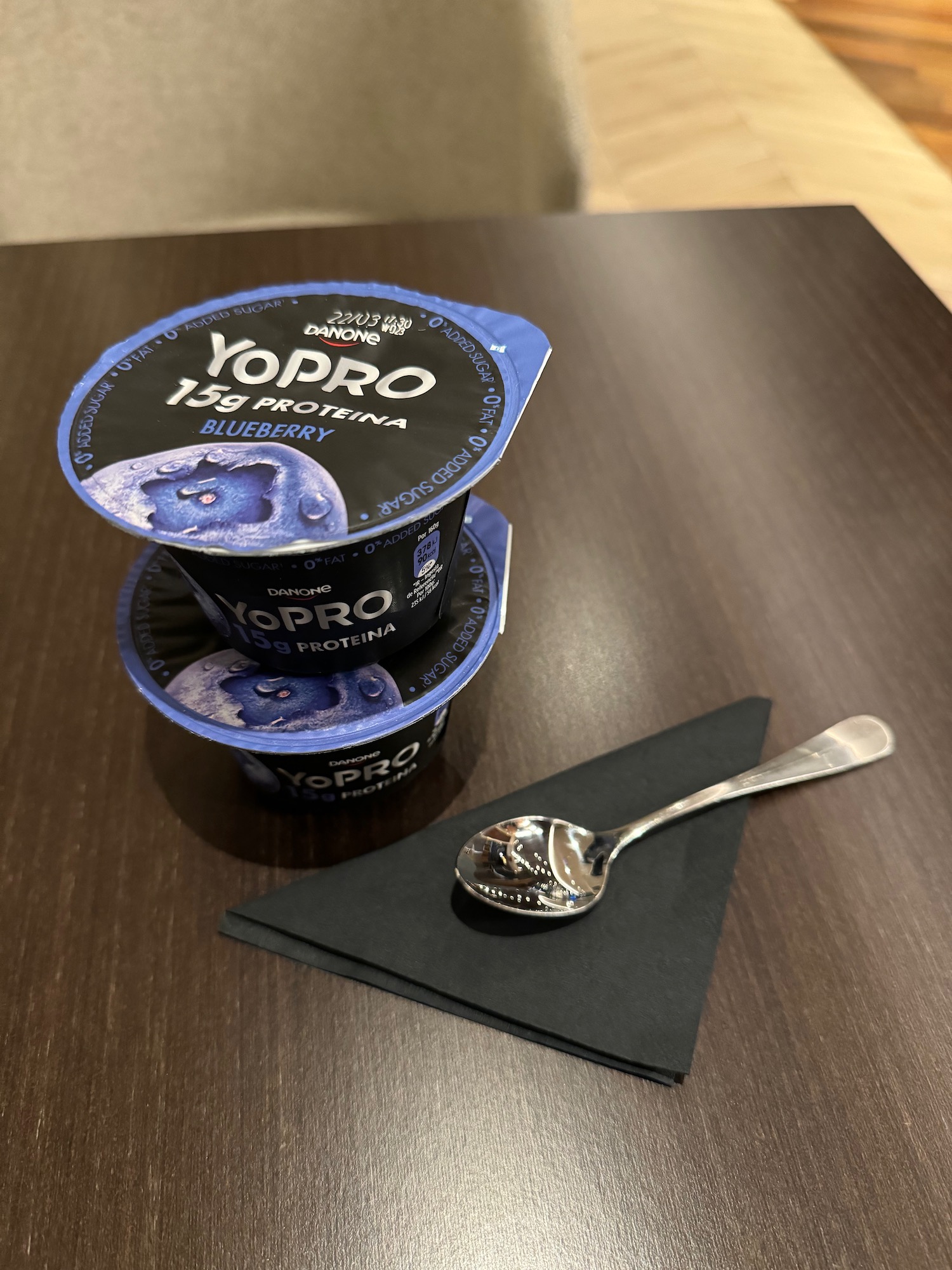 a stack of blue and white yogurt cups and a spoon on a table