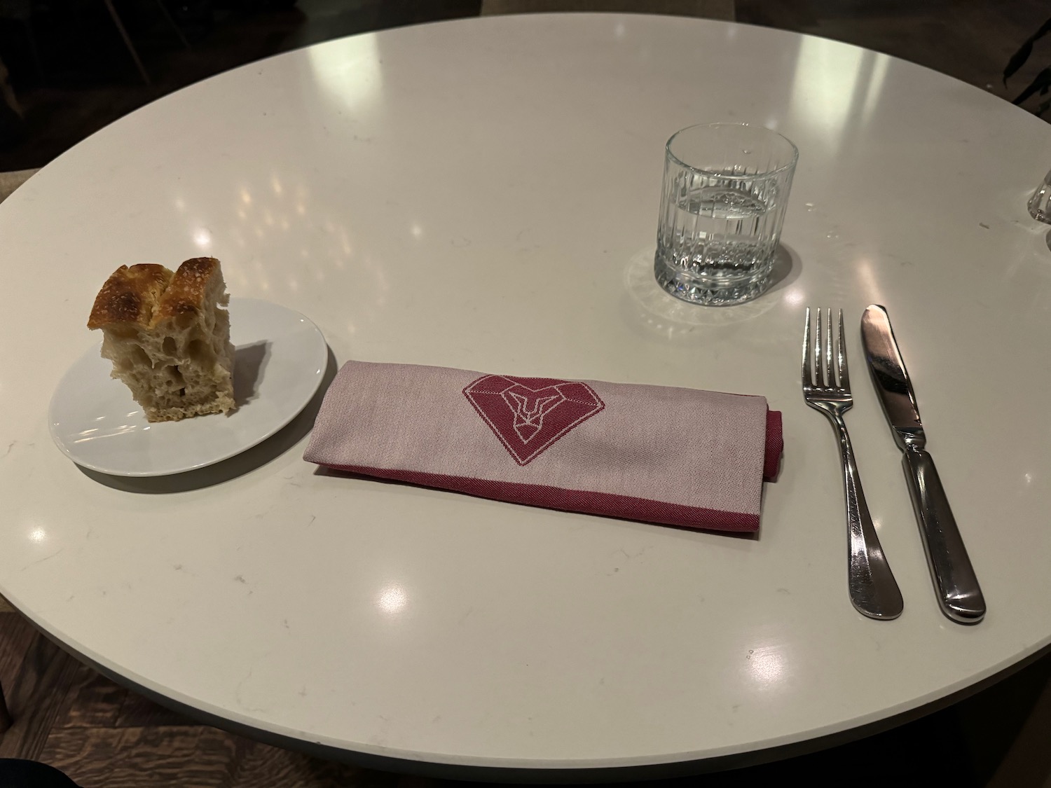 a plate with a piece of bread on it and a napkin and fork on a table