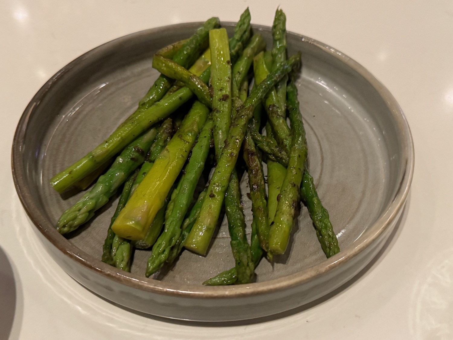 a plate of asparagus on a white surface