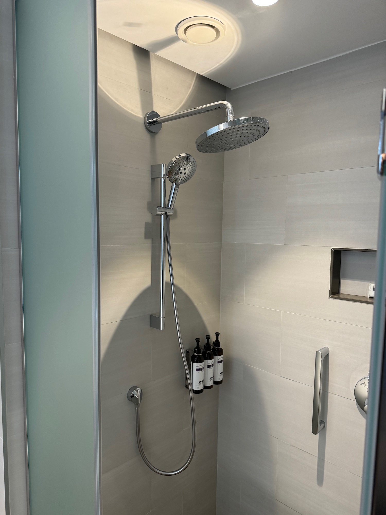 a shower with a shower head and bottles of wine