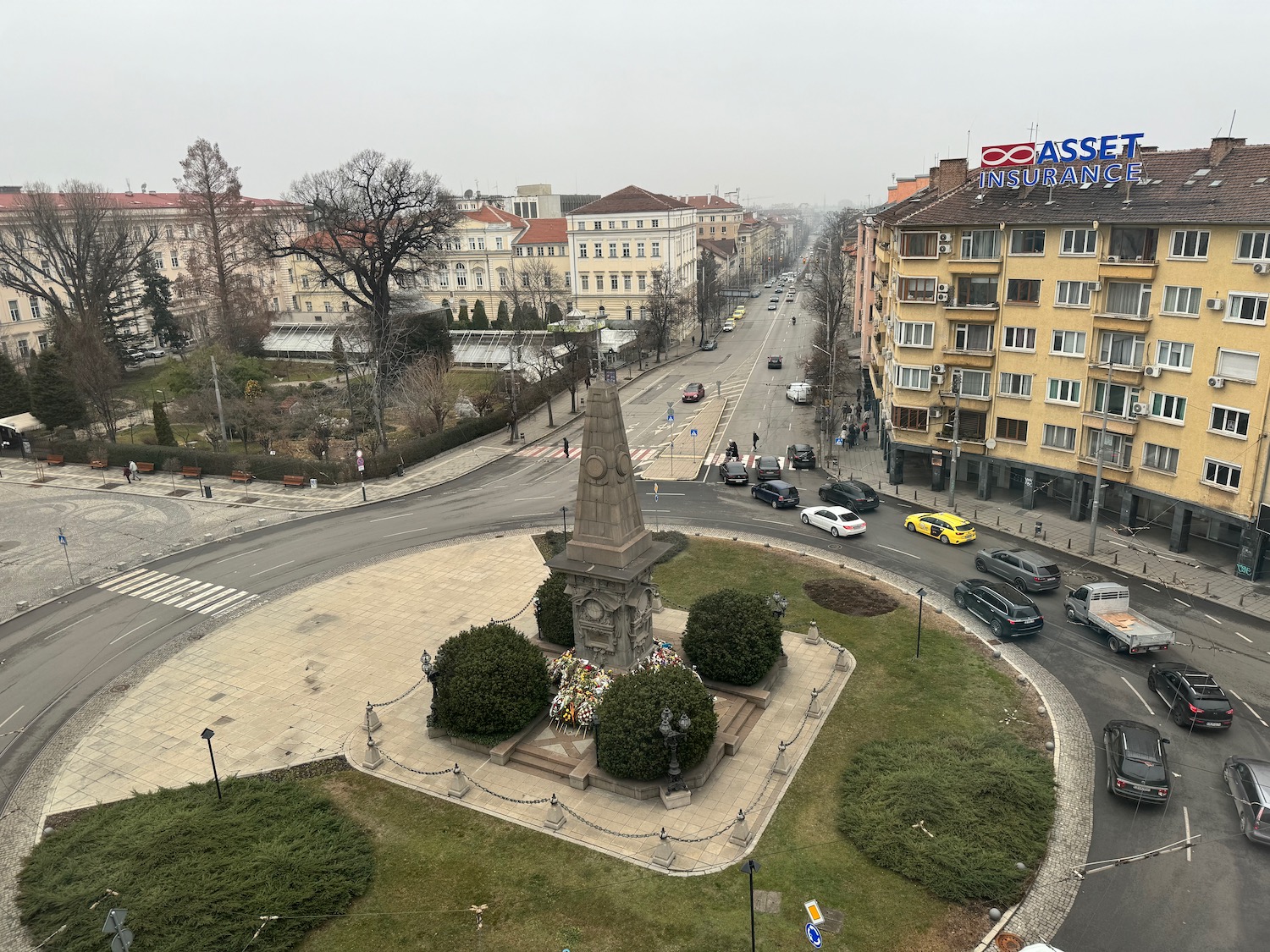 a city street with a monument and cars on the road