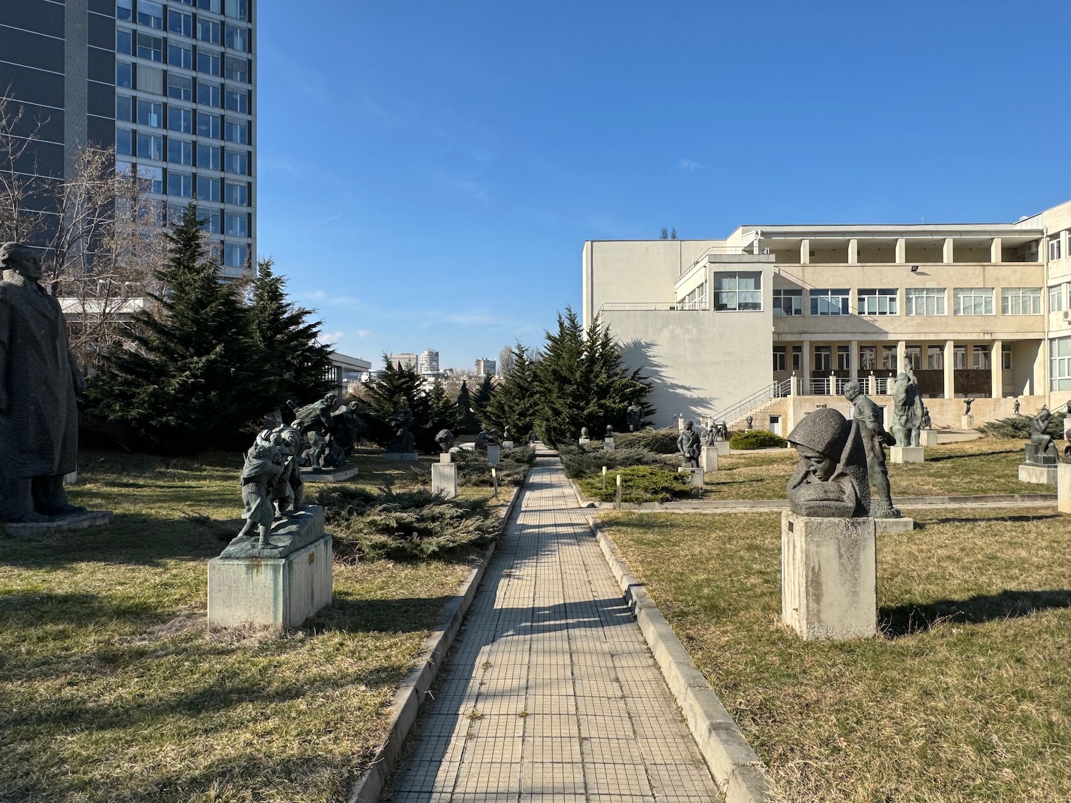 a stone walkway with statues in front of a building