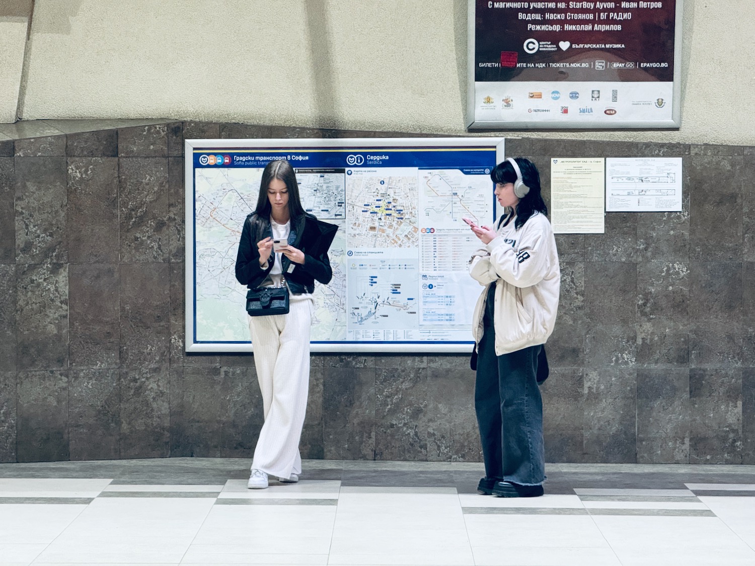 two women standing in front of a large map