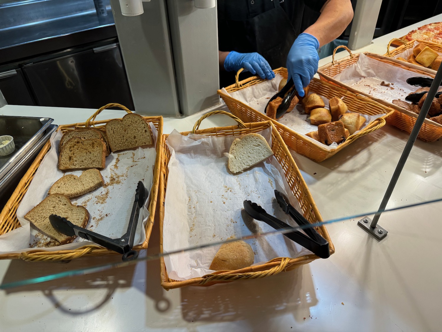 a person in gloves cutting bread in baskets