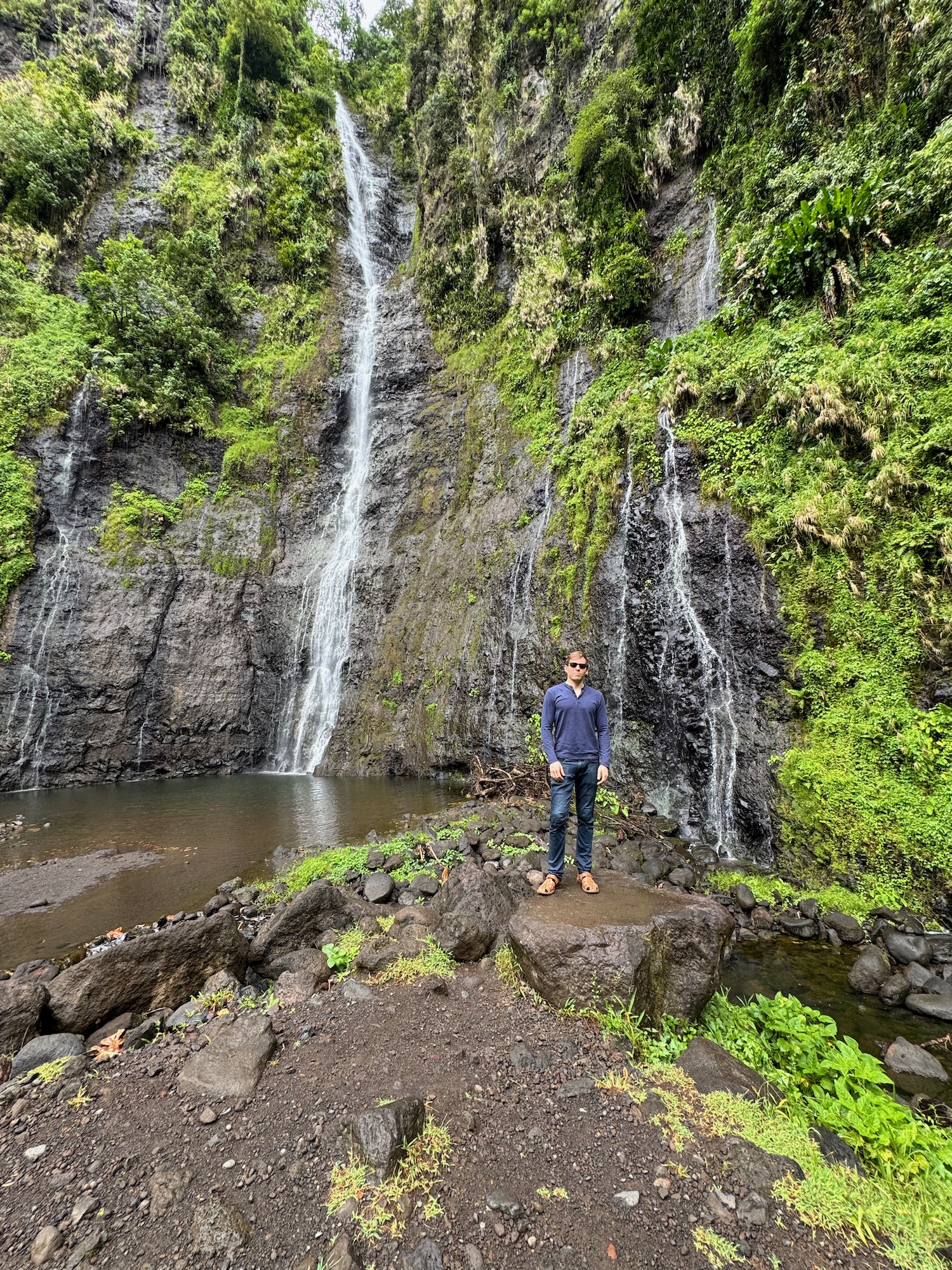 a man standing on a rock in front of a waterfall