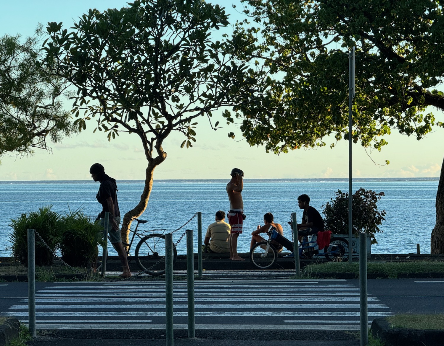 a group of people sitting on a sidewalk by the water