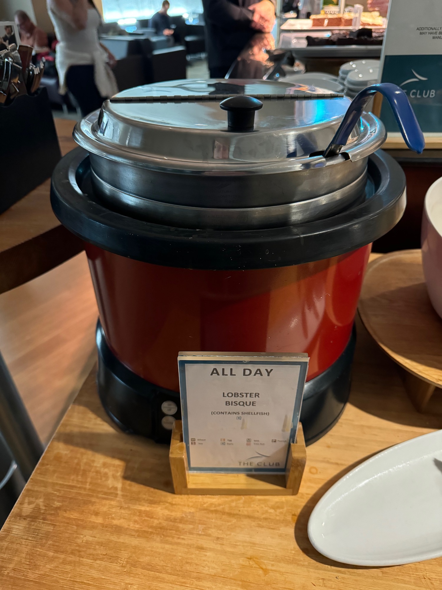 a red and black pot with a lid and a sign on a table