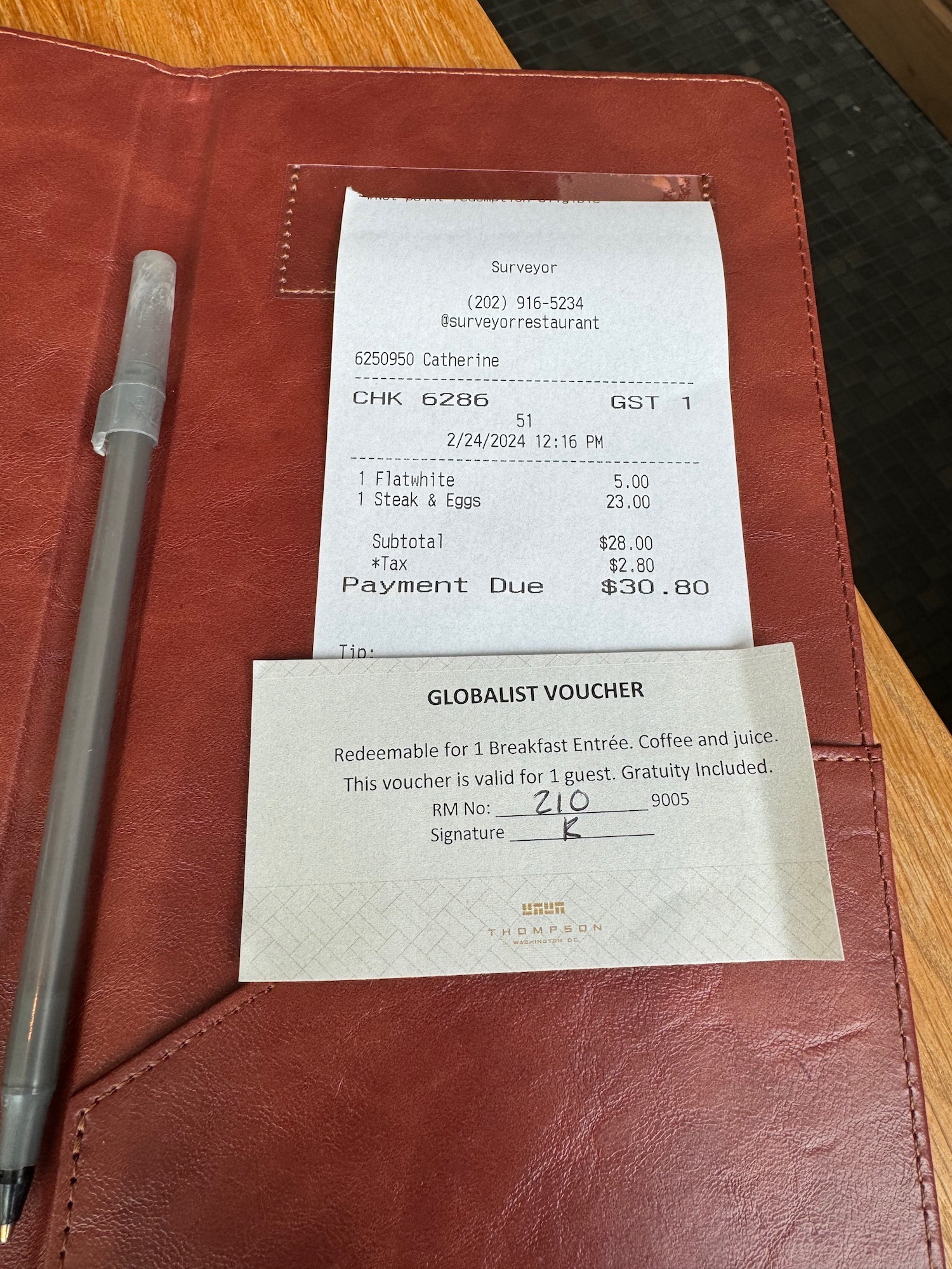 a receipt and a pen on a red leather cover