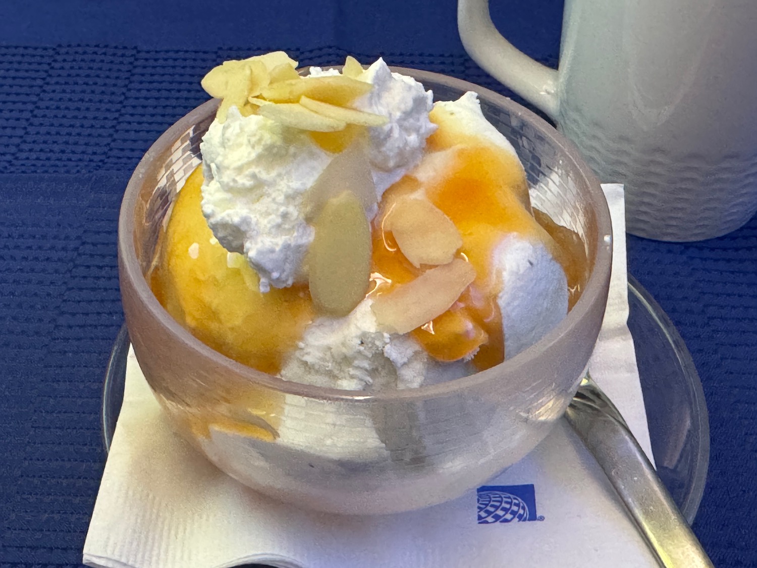 a bowl of ice cream with almonds and a spoon