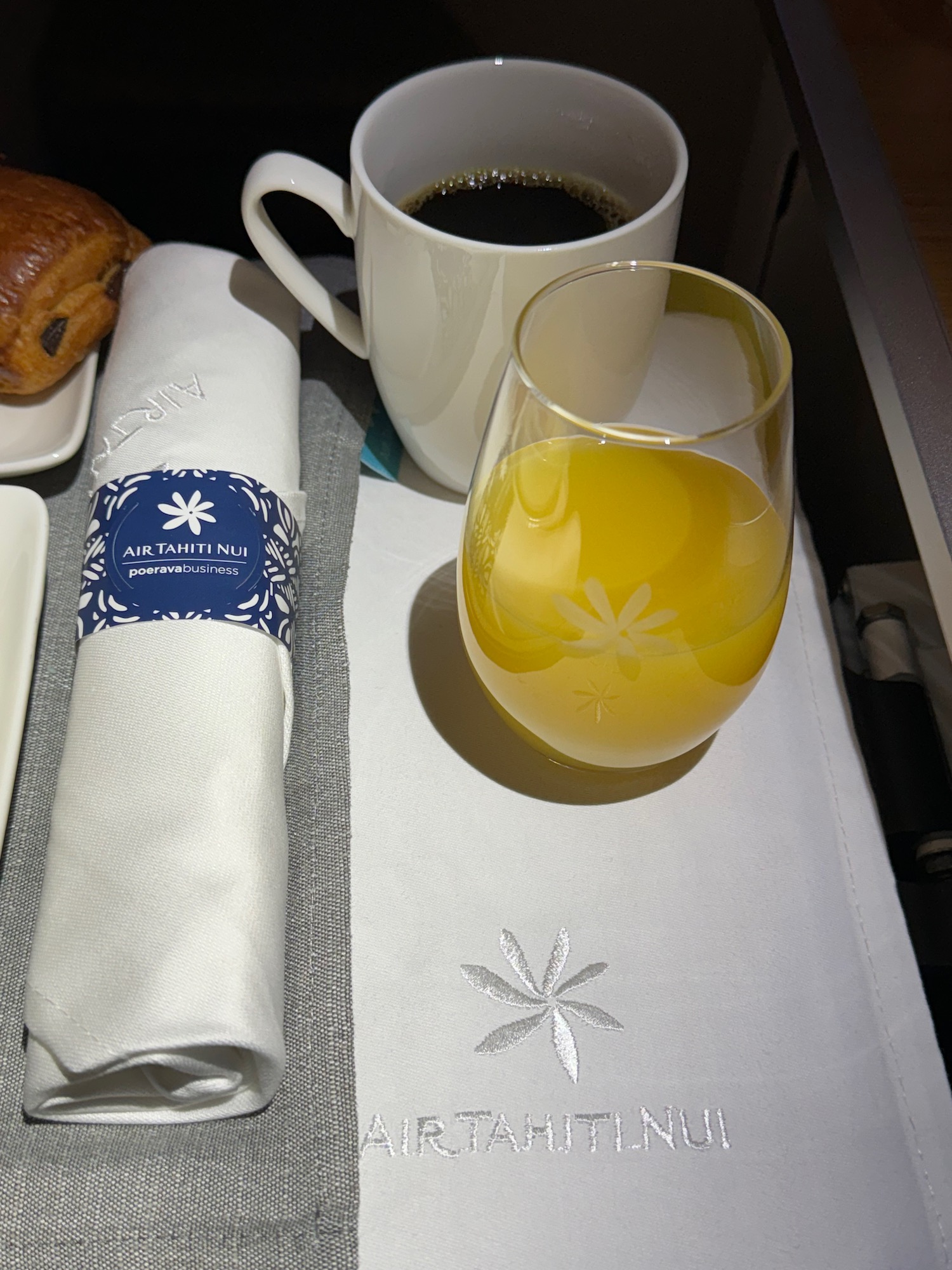 a glass of orange juice and a napkin on a tray