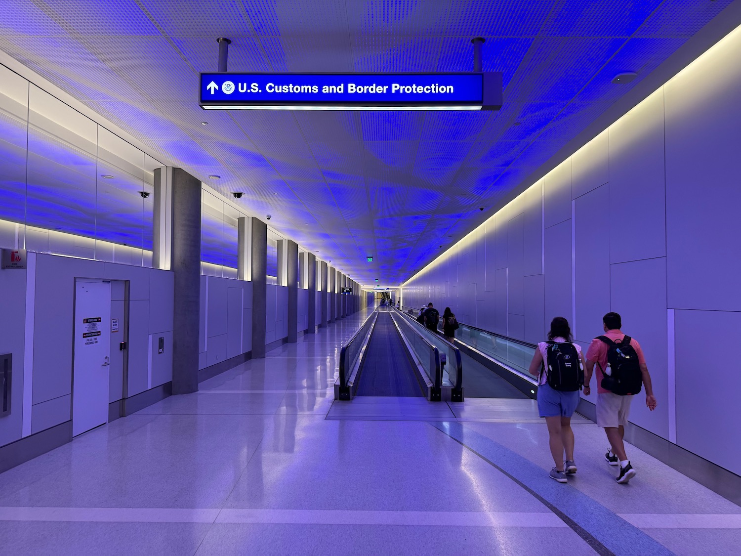 people walking down a walkway with a sign