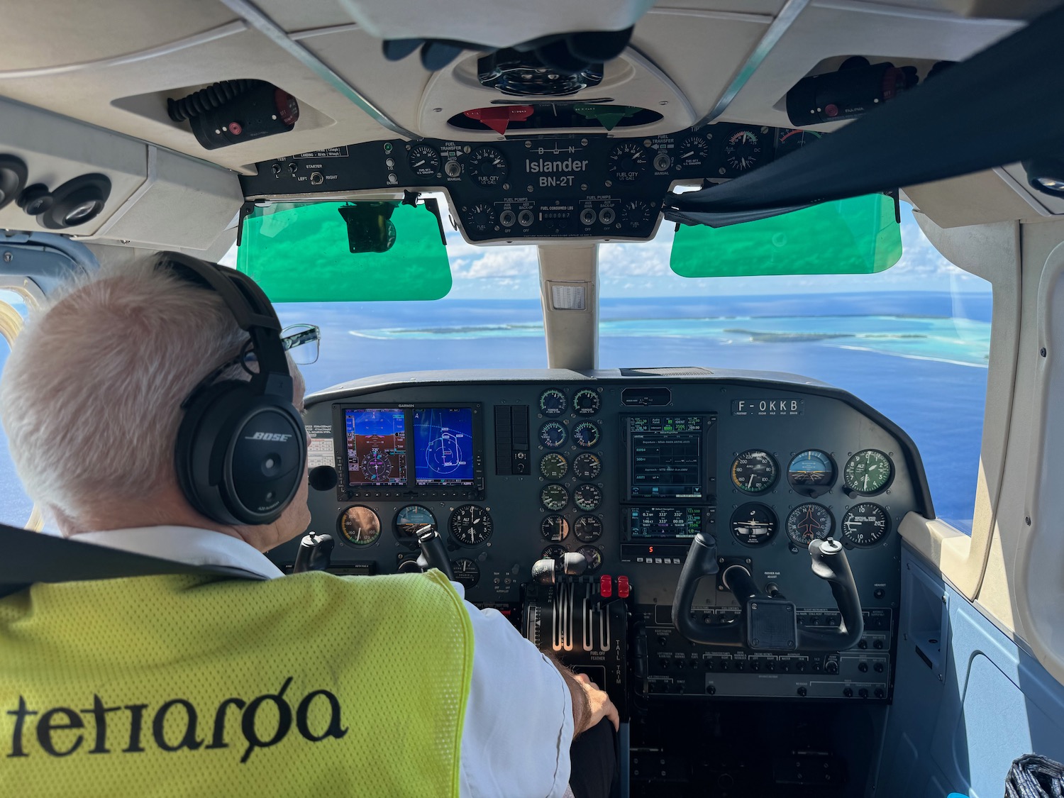 a man in a yellow vest and headphones in a plane cockpit