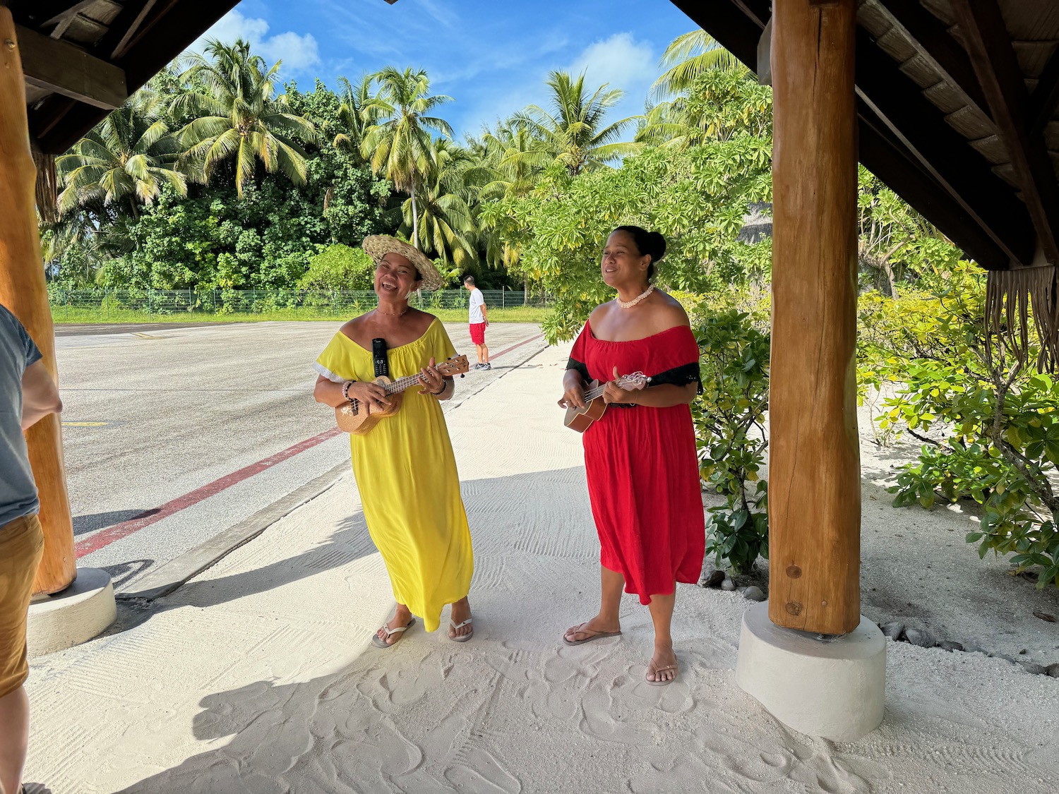 two women playing ukuleles under a shelter