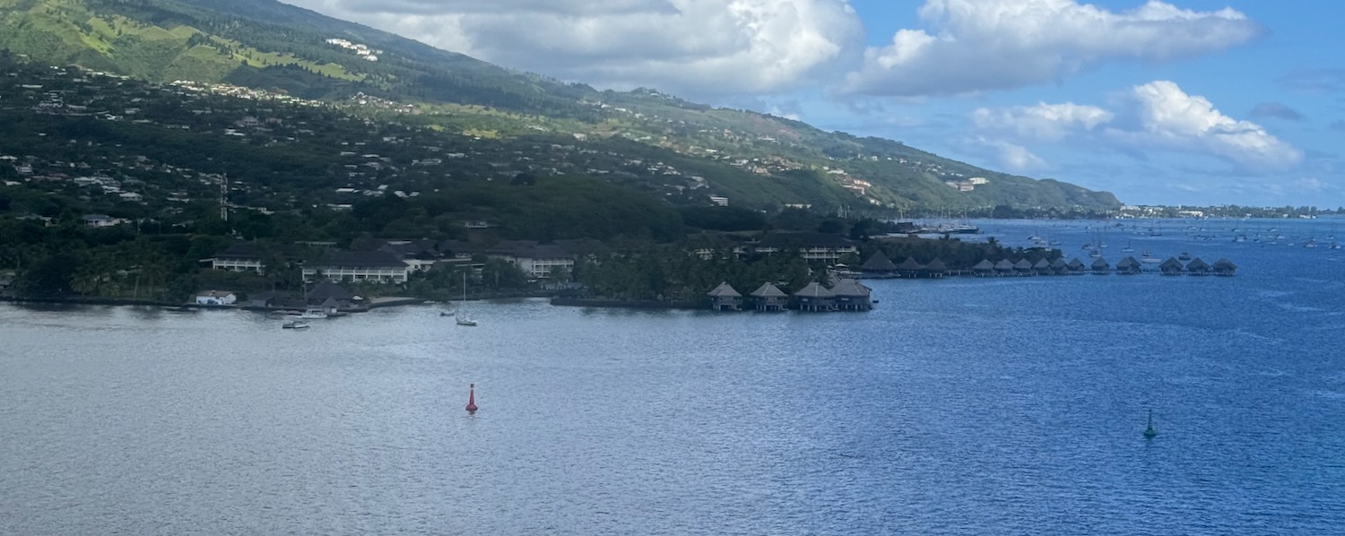 a body of water with buildings and a hill in the background