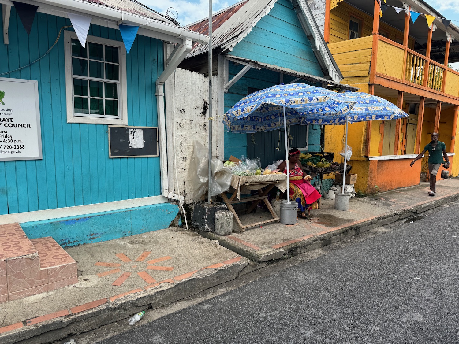 a woman sitting under an umbrella outside of a colorful building