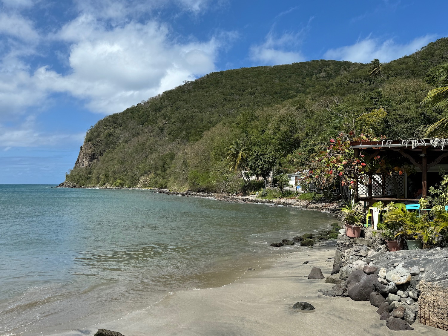 a beach with a house and a hill